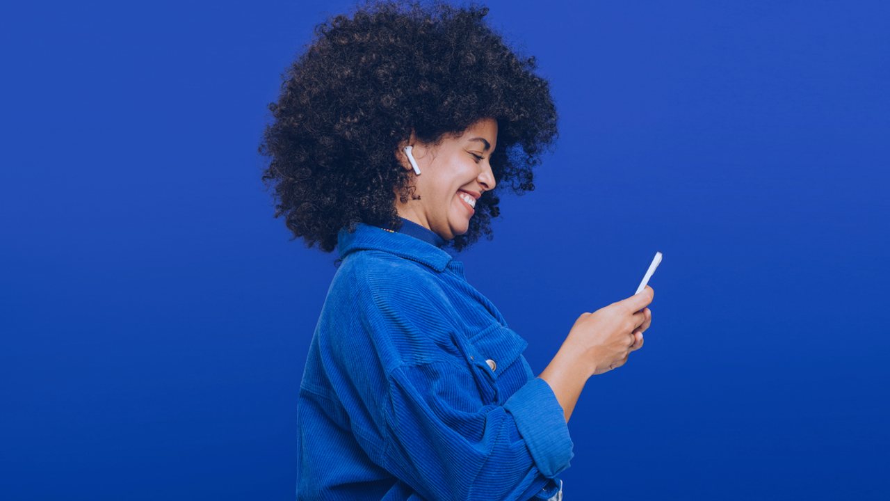 Mulher usando o celular com fundo e roupa azuis, ilustrando criar um chatbot no whatsapp