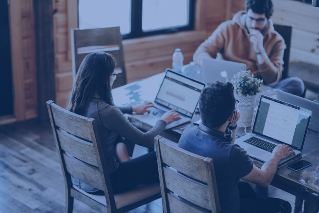 Pessoas na mesa de trabalho com seus notebooks checando as extensões de data e analytics